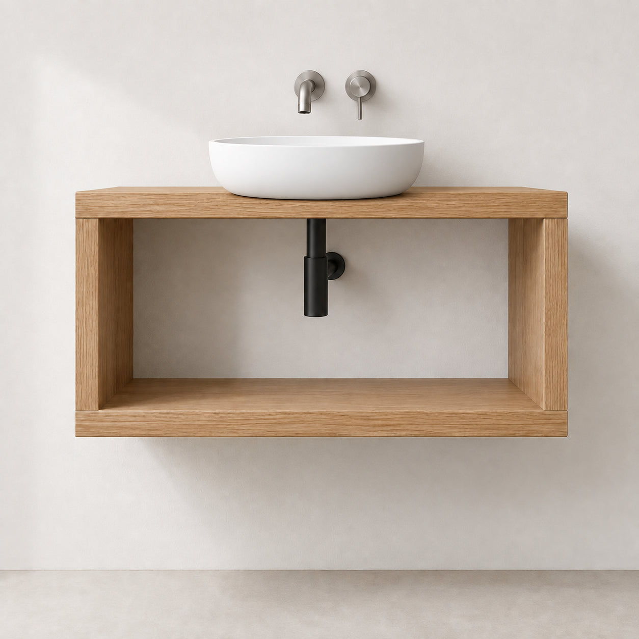 A modern floating vanity with a light oak wood frame and open shelf, holding a white vessel sink with two matte silver wall-mounted faucets, set against a warm beige wall.