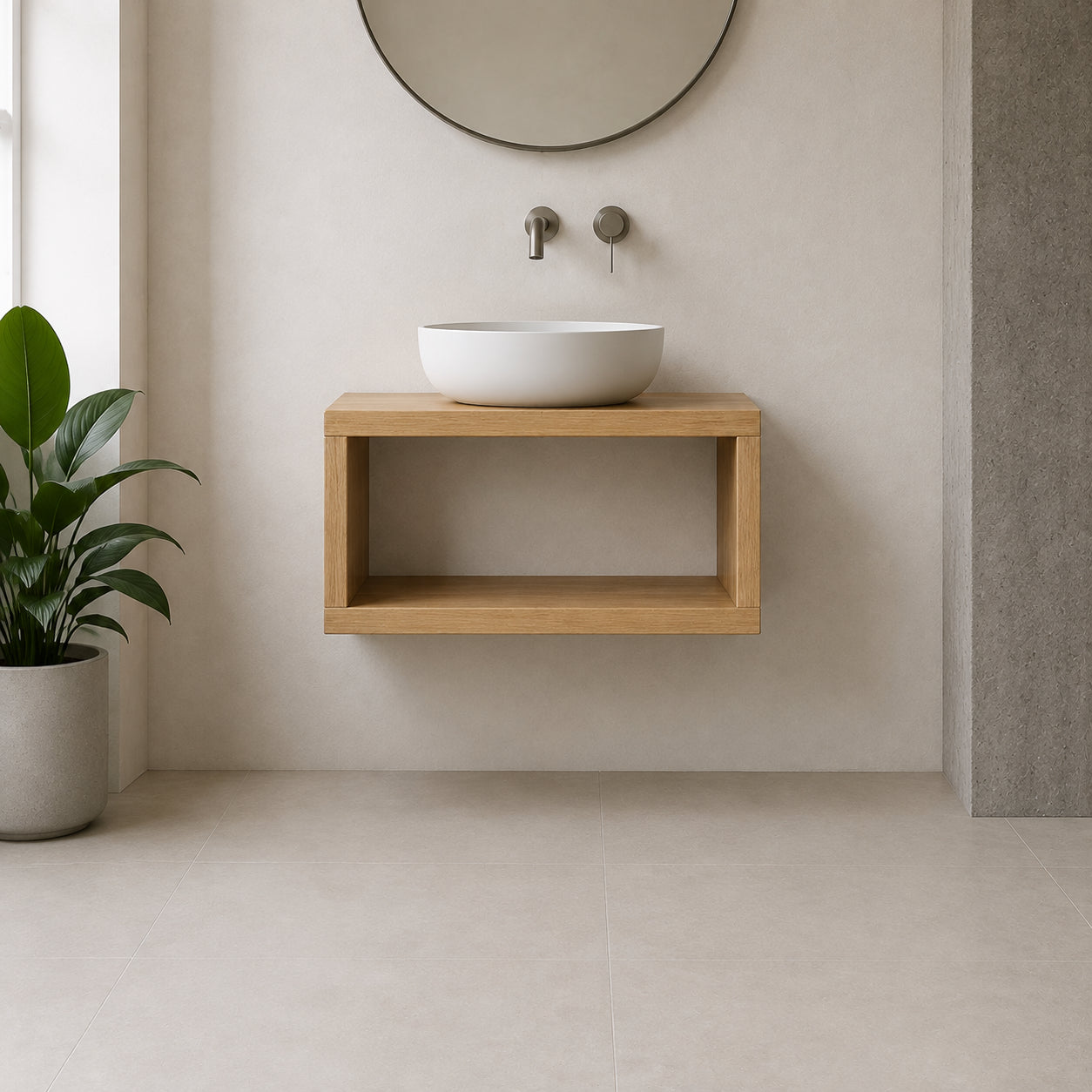 A modern floating wooden vanity shelf with an open cubby holding a white vessel sink, set against a minimalist beige wall with a round mirror and wall-mounted faucets. A potted green plant is visible on the left.