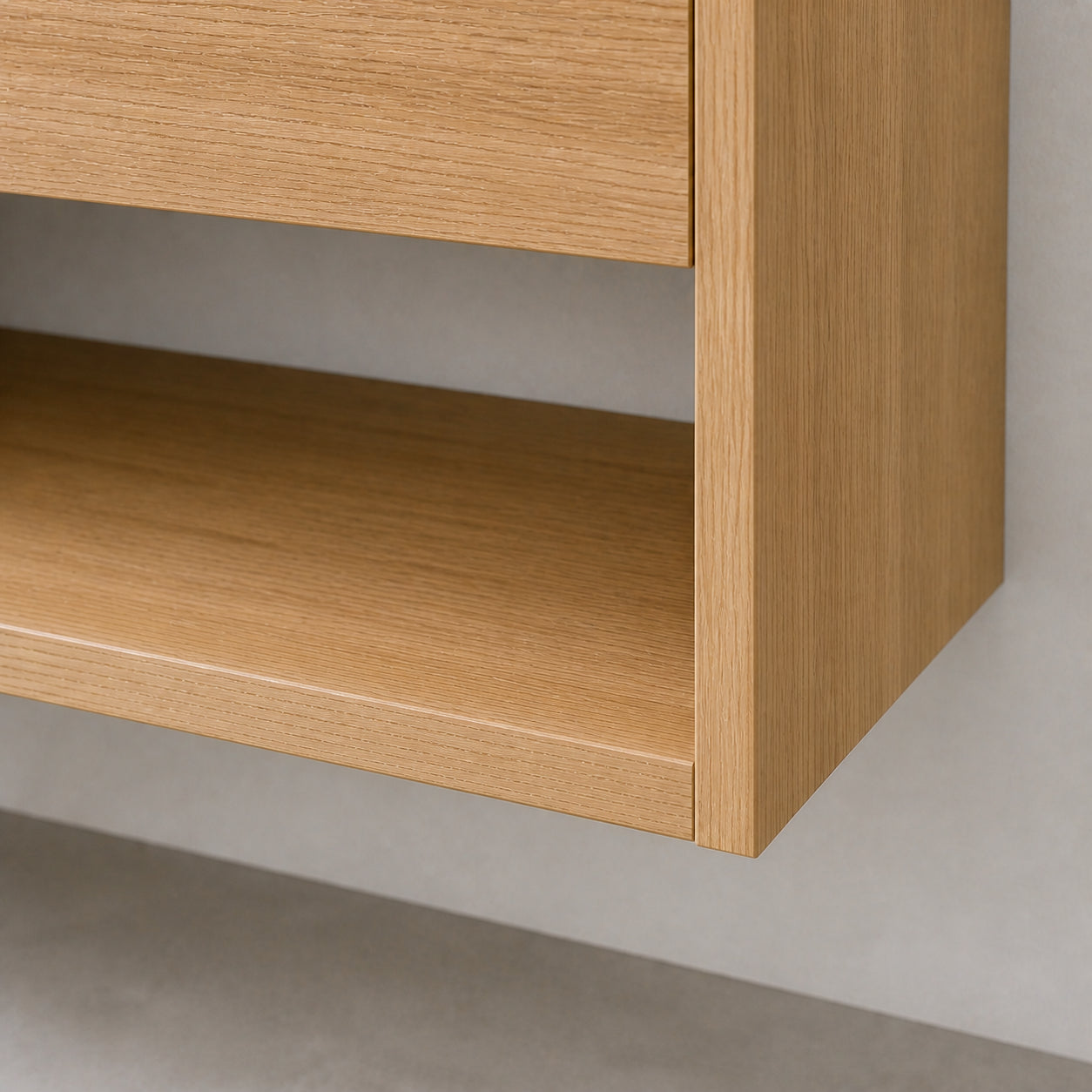 Close-up of a light oak wood floating shelf or cabinet corner against a neutral gray wall and concrete floor.