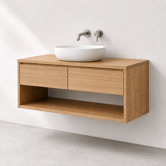 A modern wall-mounted bathroom vanity in light oak wood with two drawers and an open lower shelf, holding a white oval vessel sink with a matte faucet set against a white wall.